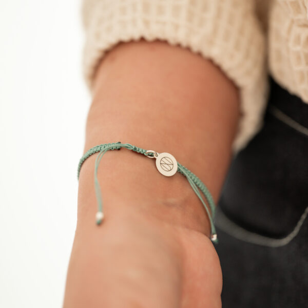 Zadní strana náramku Turquoise Time s posuvným zapínáním se stříbrným kruhovým plíškem s monogramem značky